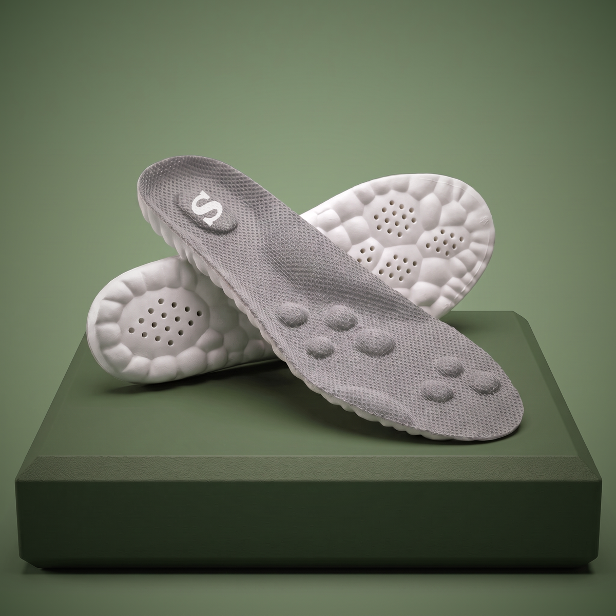 Pair of Solacea plantar fasciitis insoles on a sage plinth, showing the cushioned massage domes and deep heel cup